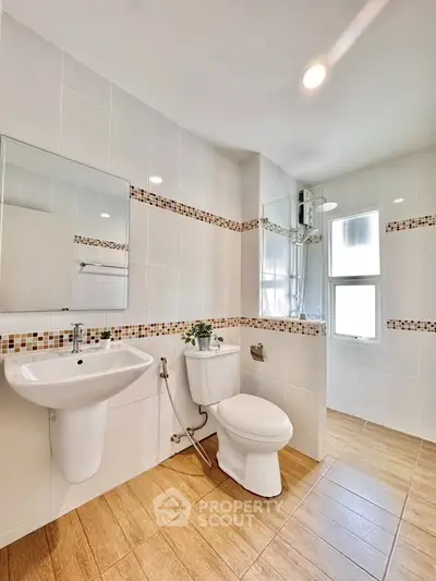 Modern bathroom with sleek fixtures and stylish tile accents, featuring a shower and natural light.