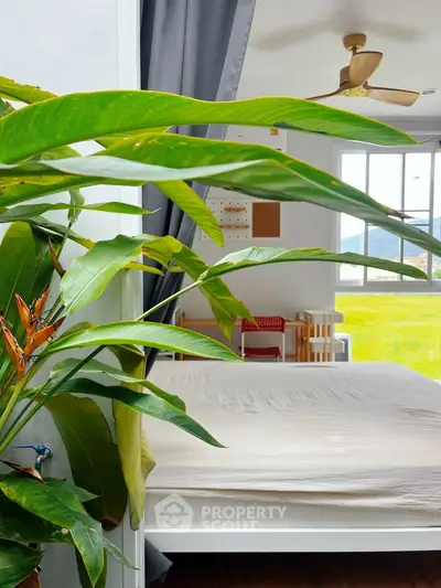 Bright bedroom with large window and scenic view, featuring modern decor and ceiling fan.