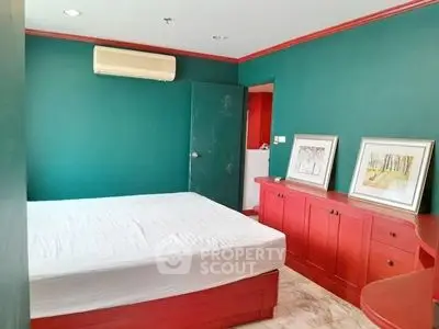 Vibrant bedroom with green walls and red furniture, featuring a cozy bed and stylish decor.