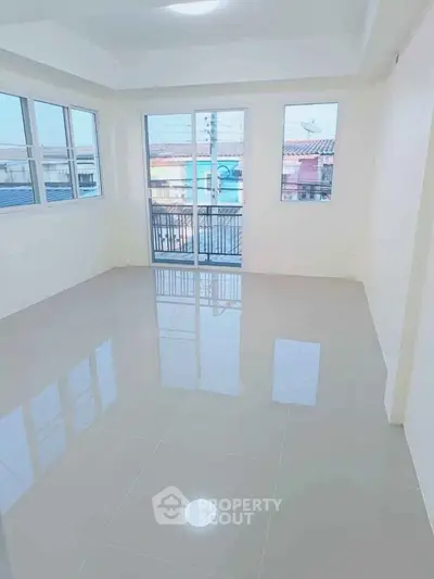 Bright and spacious living room with large windows and glossy tiled floor, offering ample natural light.