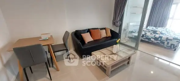 Modern studio apartment with cozy living area and bedroom separated by glass partition.