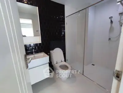 Modern bathroom with sleek black tiles and glass shower enclosure