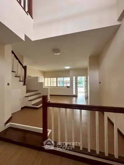 Spacious modern living room with wooden flooring and staircase, perfect for family gatherings.
