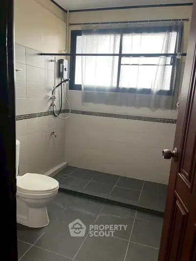 Modern bathroom with shower and toilet in a well-lit space.