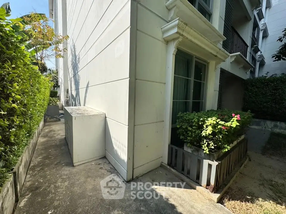 Charming exterior view of a modern building with lush greenery and a cozy balcony.