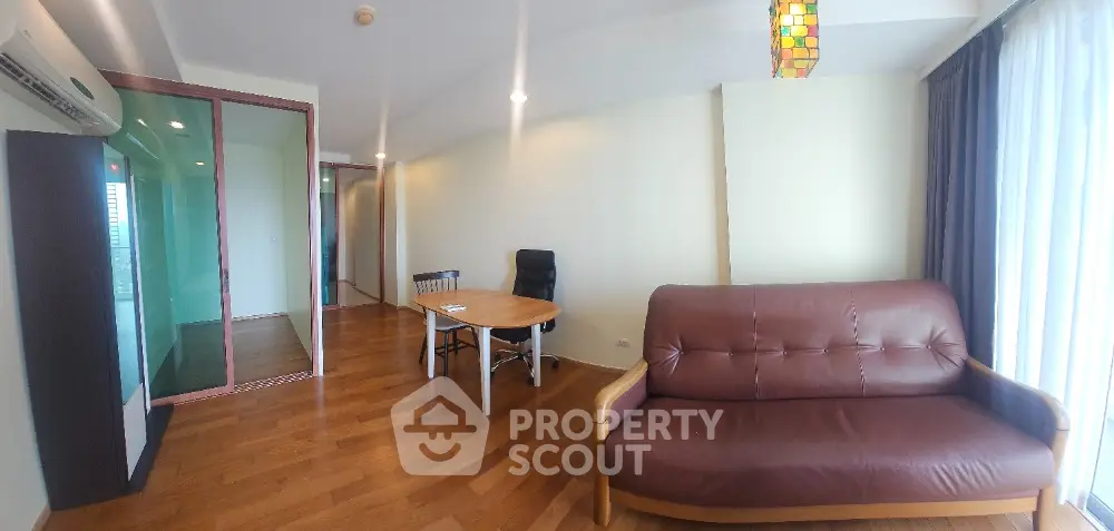 Spacious living room with wooden flooring, leather sofa, and modern lighting