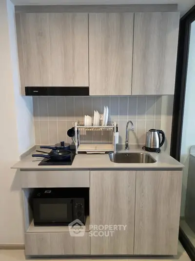 Modern compact kitchen with sleek cabinetry, induction cooktop, and built-in microwave, perfect for urban living.