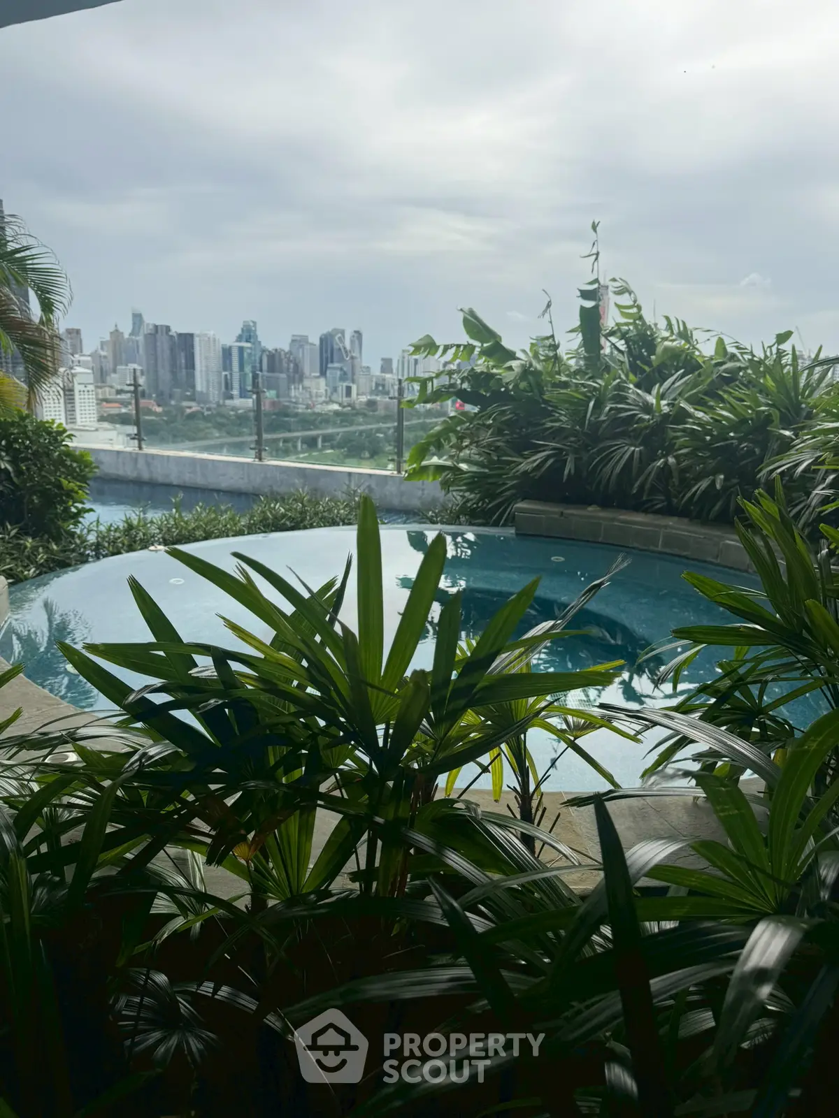 Luxurious rooftop pool with stunning city skyline view and lush greenery.