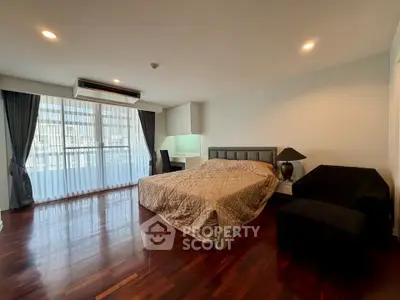 Spacious bedroom with elegant hardwood floors and large window for natural light.