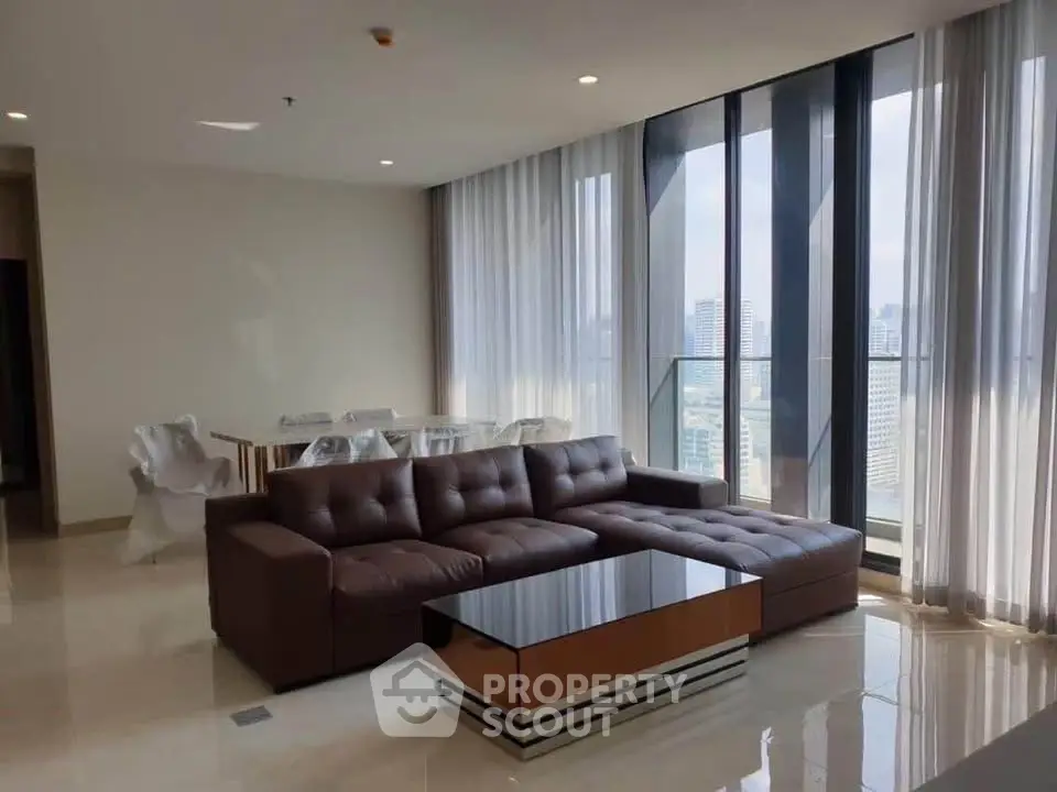 Luxurious living room with modern furniture and stunning city view through floor-to-ceiling windows.