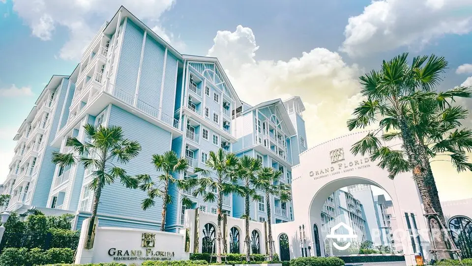 Elegant Grand Florida residential building with palm trees and classic architecture under a bright sky.