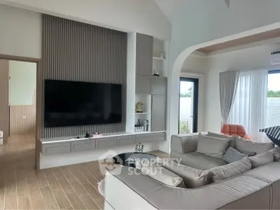 Spacious modern living room with elegant decor and large TV, perfect for relaxation and entertainment.