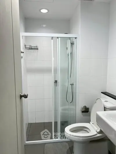 Modern bathroom with glass shower enclosure and sleek white tiles