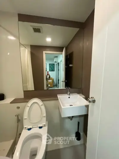 Modern bathroom with sleek fixtures and large mirror in a contemporary apartment.