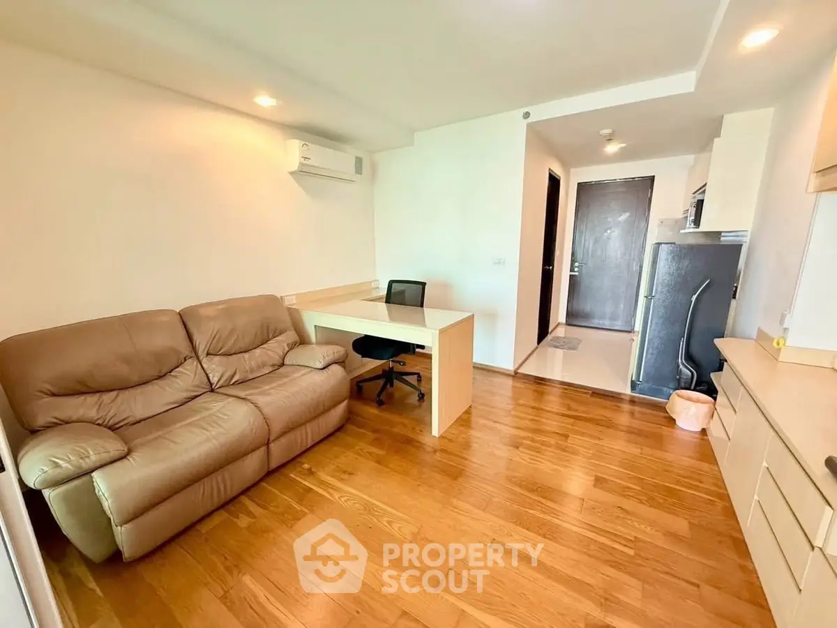 Modern living room with wooden flooring, cozy sofa, and study desk in a bright apartment.