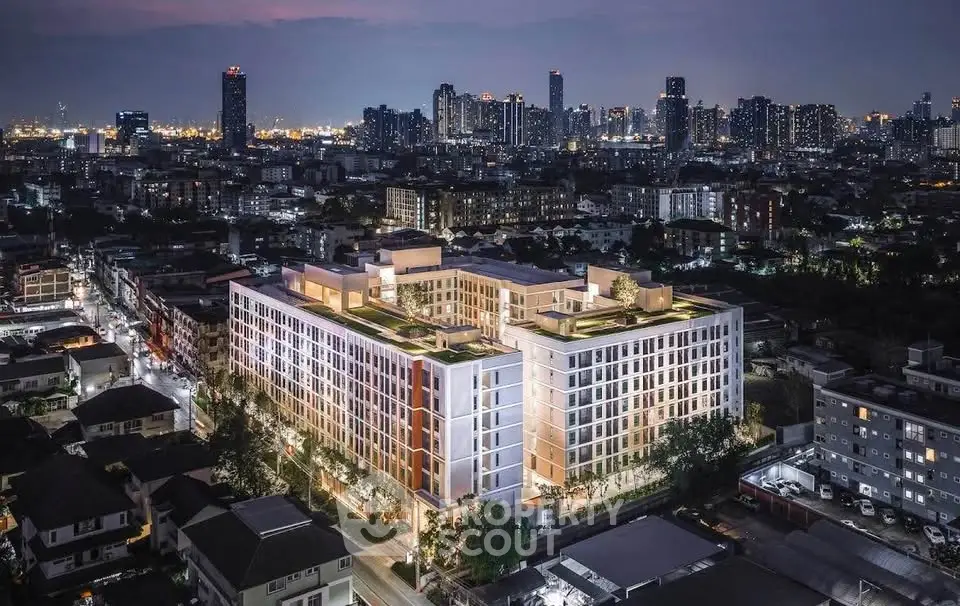 Stunning aerial view of modern apartment building with city skyline at night, showcasing urban living.