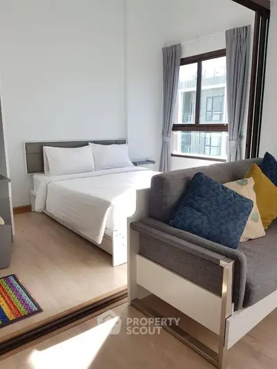 Modern bedroom with cozy seating area and large window for natural light