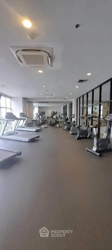Spacious modern gym with state-of-the-art equipment and large mirrors in a luxury residential building.
