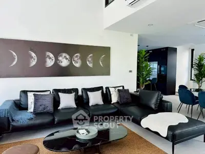 Modern living room with black leather sofa and moon phase artwork