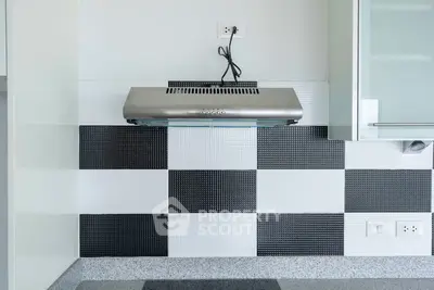 Modern kitchen with stylish black and white checkered backsplash and stainless steel range hood.
