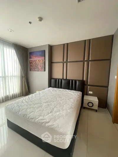 Spacious bedroom with modern decor and large window offering natural light.