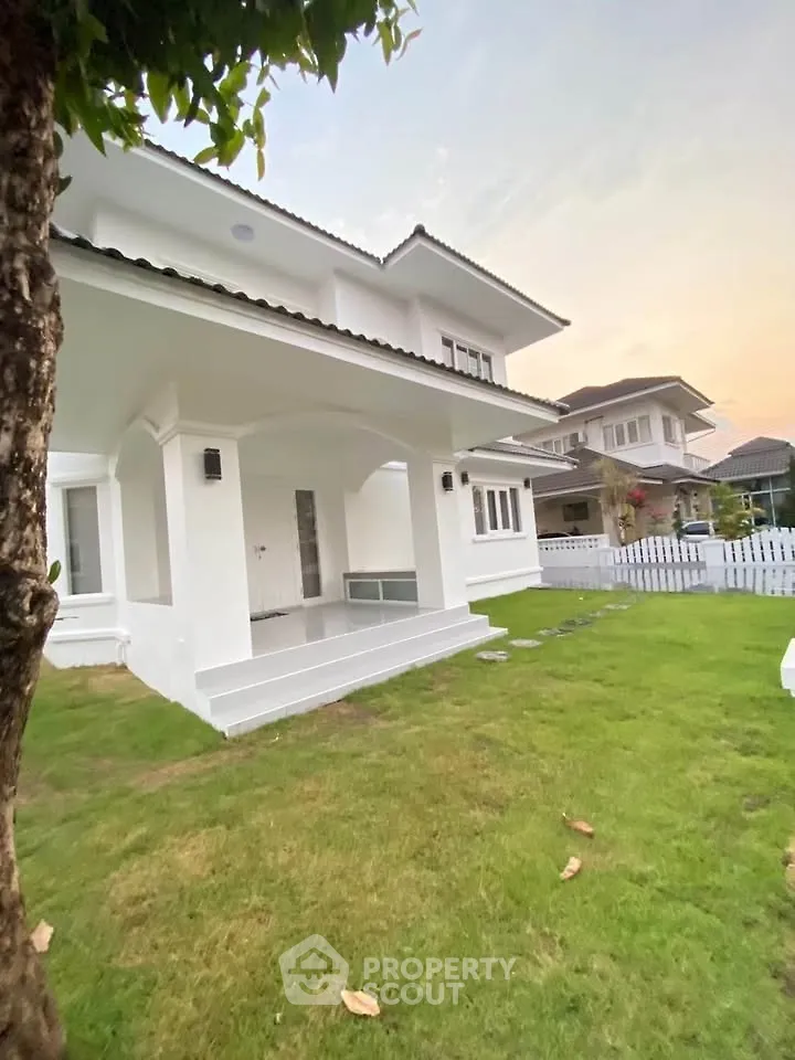 Charming two-story white house with lush green lawn and modern architecture in a serene neighborhood.