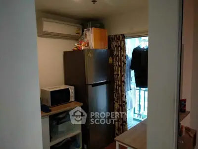 Compact kitchen with fridge, microwave, and balcony access in modern apartment.