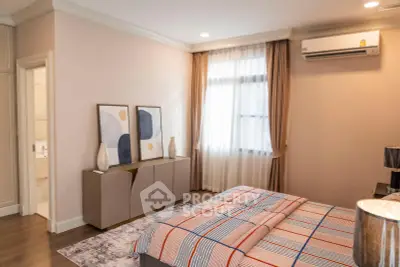 Elegant bedroom with modern decor and natural light, featuring stylish artwork and air conditioning.