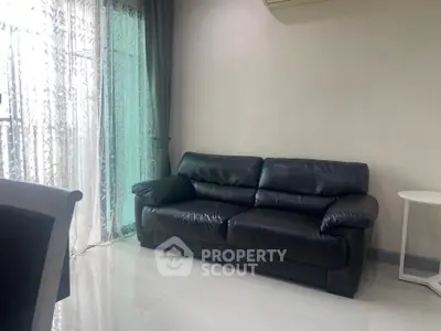 Modern living room with sleek black leather sofa and elegant curtains, perfect for stylish urban living.