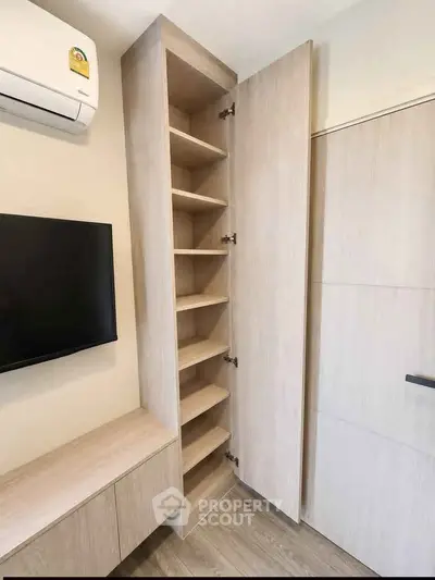 Modern storage cabinet in a sleek interior with wall-mounted TV and air conditioning unit.