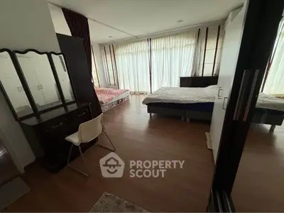 Spacious bedroom with large windows and elegant wooden flooring