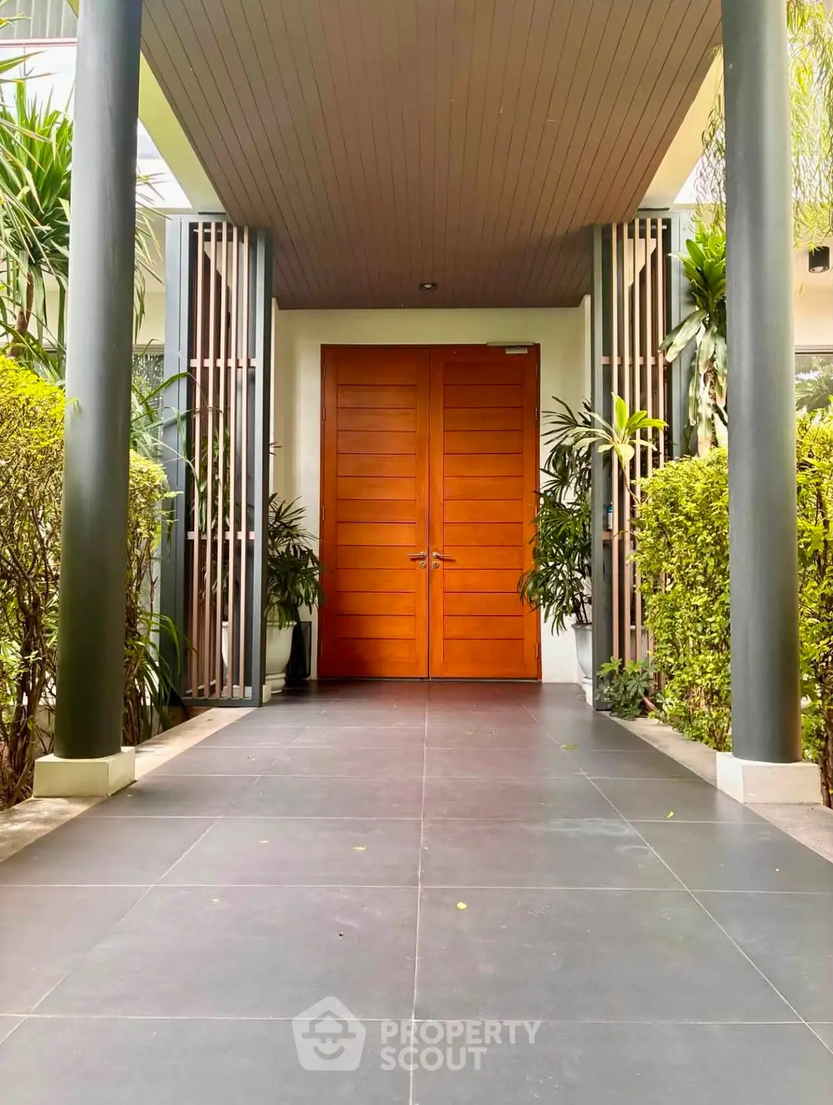 Elegant entrance with wooden double doors and lush greenery, perfect for a welcoming home ambiance.