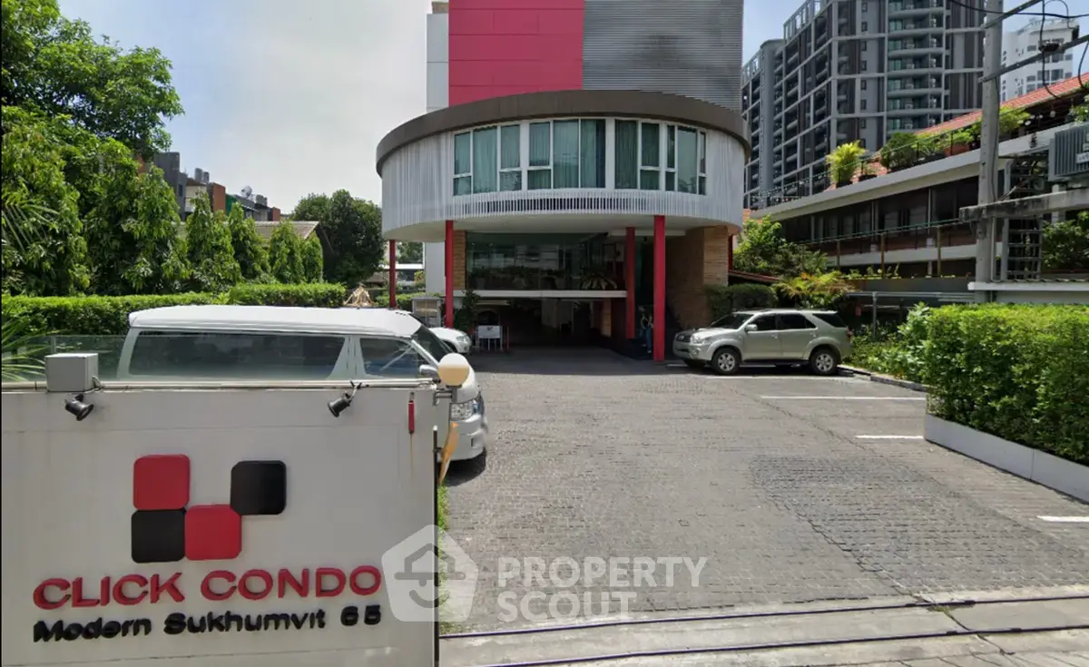 Modern condo entrance with sleek design in Sukhumvit 65, lush greenery and ample parking space.