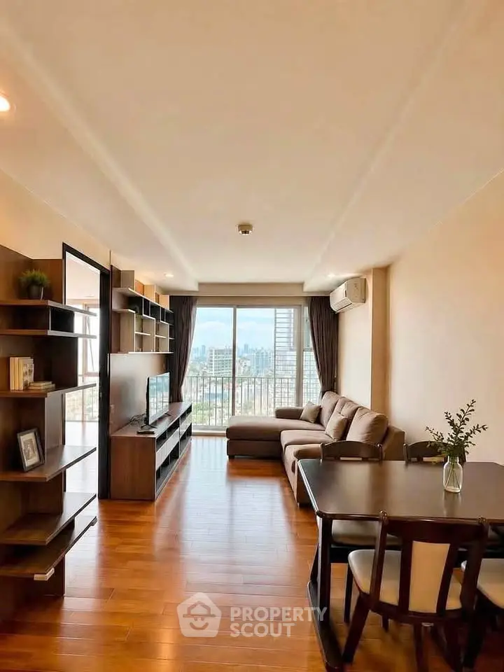 Spacious living room with city view, modern furniture, and wooden flooring in a high-rise apartment.