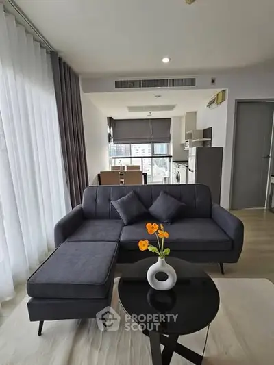 Modern living room with sleek furniture and open kitchen layout in a stylish apartment.