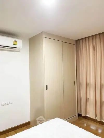 Cozy bedroom with modern wardrobe and air conditioning, perfect for comfortable living.