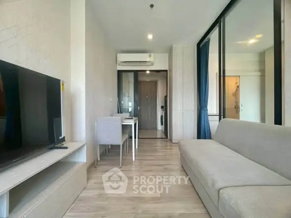 Modern living room with sleek furniture and natural light, featuring a cozy sofa and a flat-screen TV.