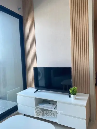 Modern living room with sleek TV stand and large window offering natural light.