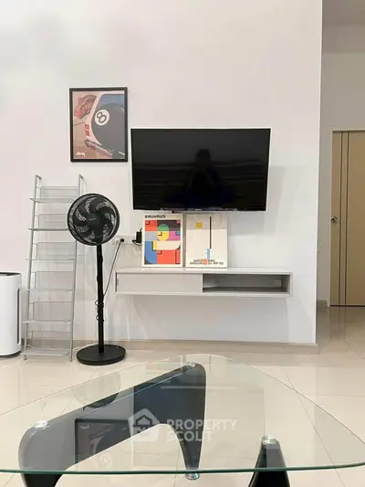 Modern living room with wall-mounted TV, sleek glass table, and stylish decor.