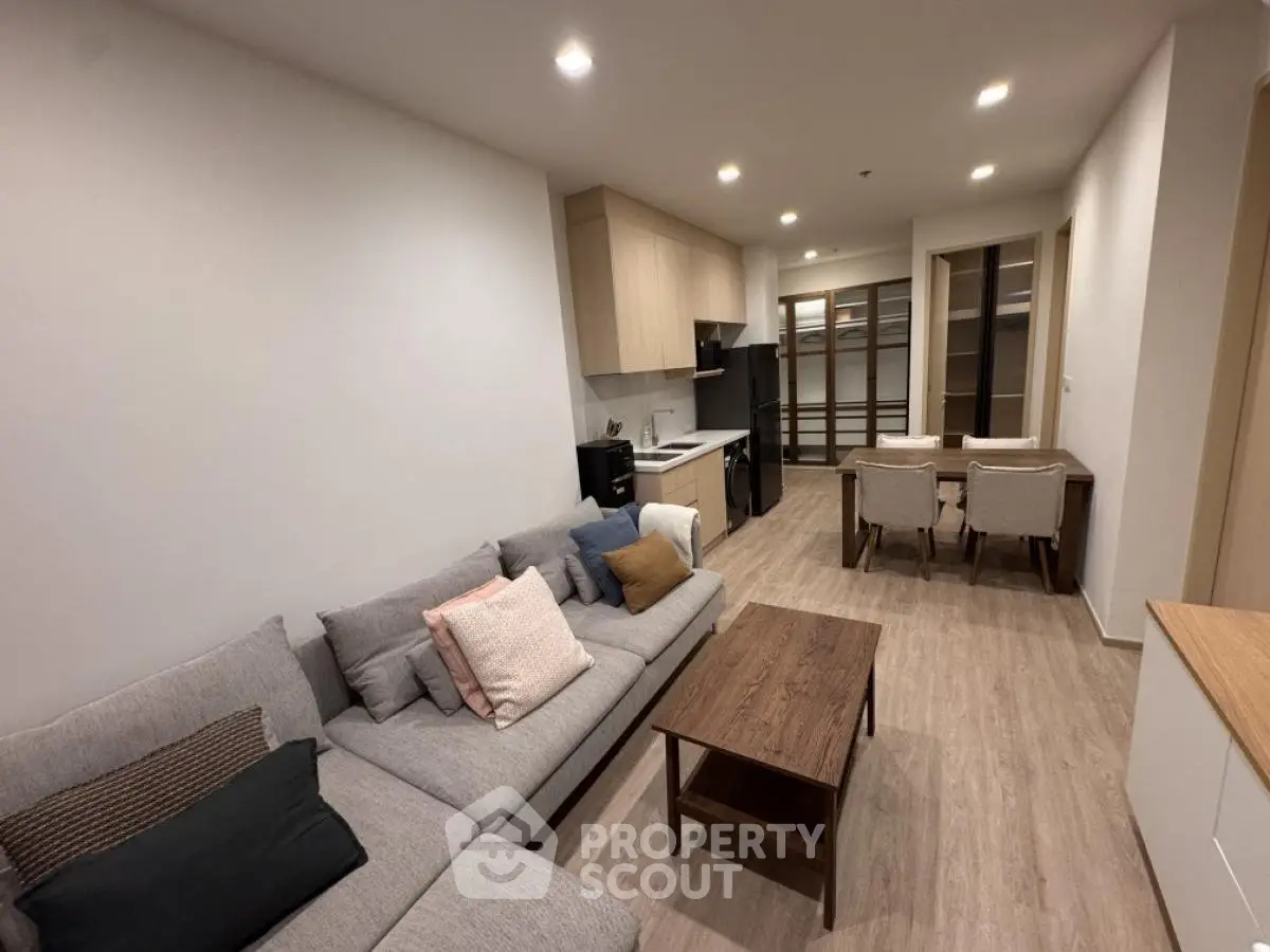 Modern living room with cozy sofa and open kitchen layout in stylish apartment.