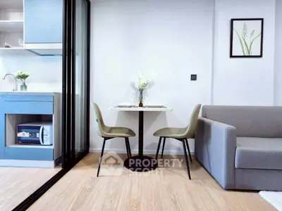 Modern compact living room with dining area and kitchenette, featuring sleek furniture and stylish decor.