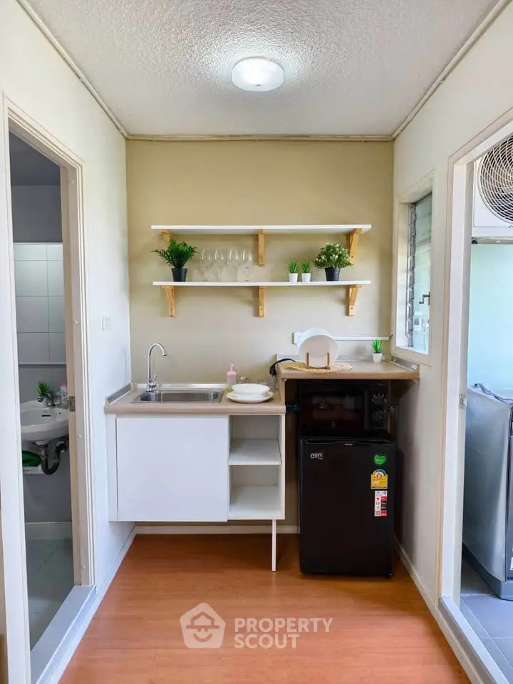 Compact kitchen with modern appliances and open shelving in cozy apartment