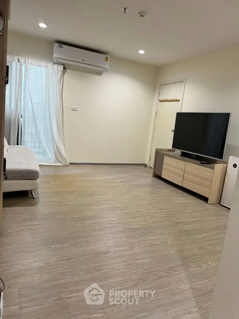 Spacious modern living room with sleek wooden flooring and large TV setup.