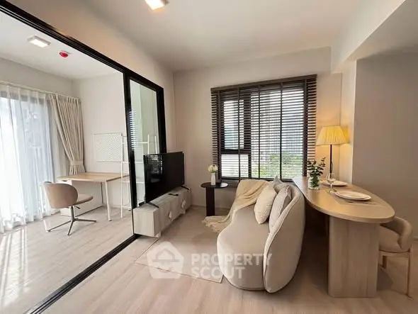 Modern living room with cozy seating and study area, featuring large windows and stylish decor.