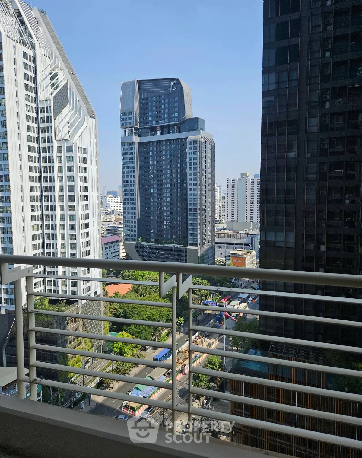Stunning cityscape view from a high-rise balcony overlooking modern skyscrapers and lush greenery.