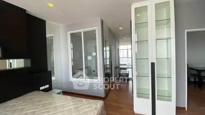 Spacious modern bedroom with glass shelving and wooden flooring in a contemporary apartment.