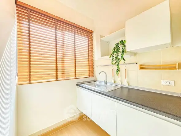 Modern kitchen with sleek cabinets and natural light, featuring a minimalist design and stylish blinds.