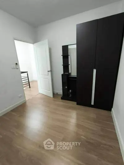 Spacious bedroom with wooden flooring and modern wardrobe in a minimalist design.