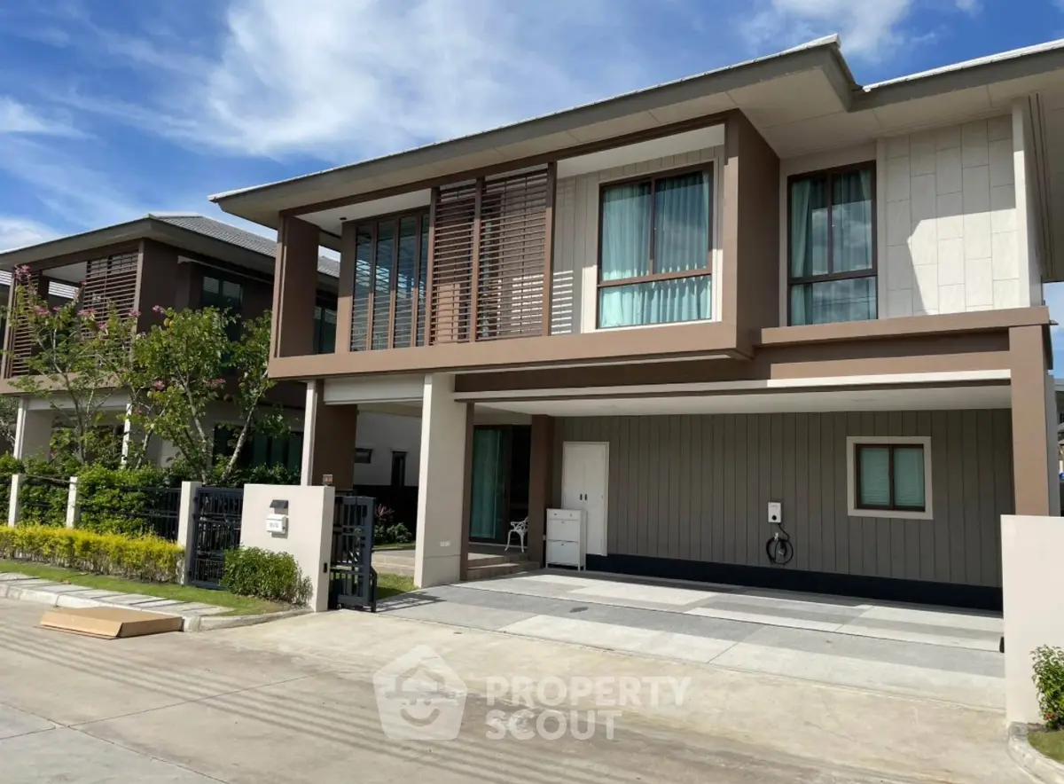 Modern two-story house with large windows and driveway in a suburban neighborhood.