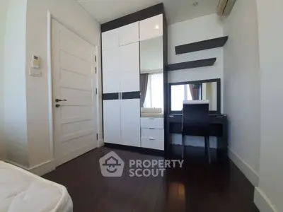 Modern bedroom with sleek furniture and hardwood floors, featuring a stylish wardrobe and vanity area.